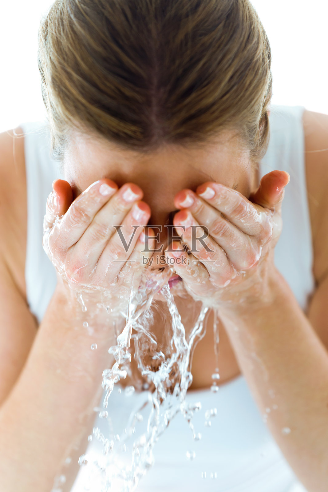 一个漂亮的年轻女子在家里的浴室里洗着脸，溅着水。照片摄影图片