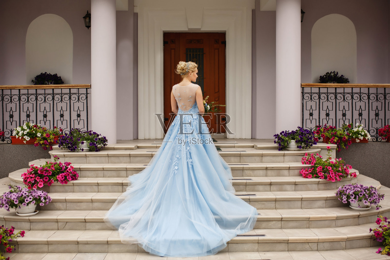 的婚礼。穿着蓝色婚纱的新娘站在带花的楼梯上照片摄影图片