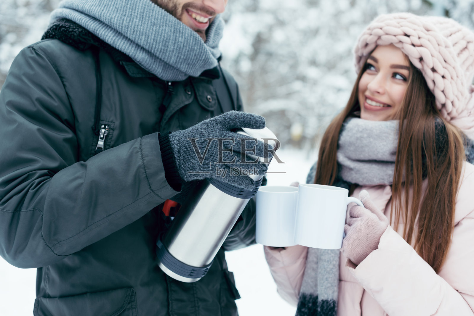 在冬季公园从热水瓶喝茶的夫妇的部分观点照片摄影图片