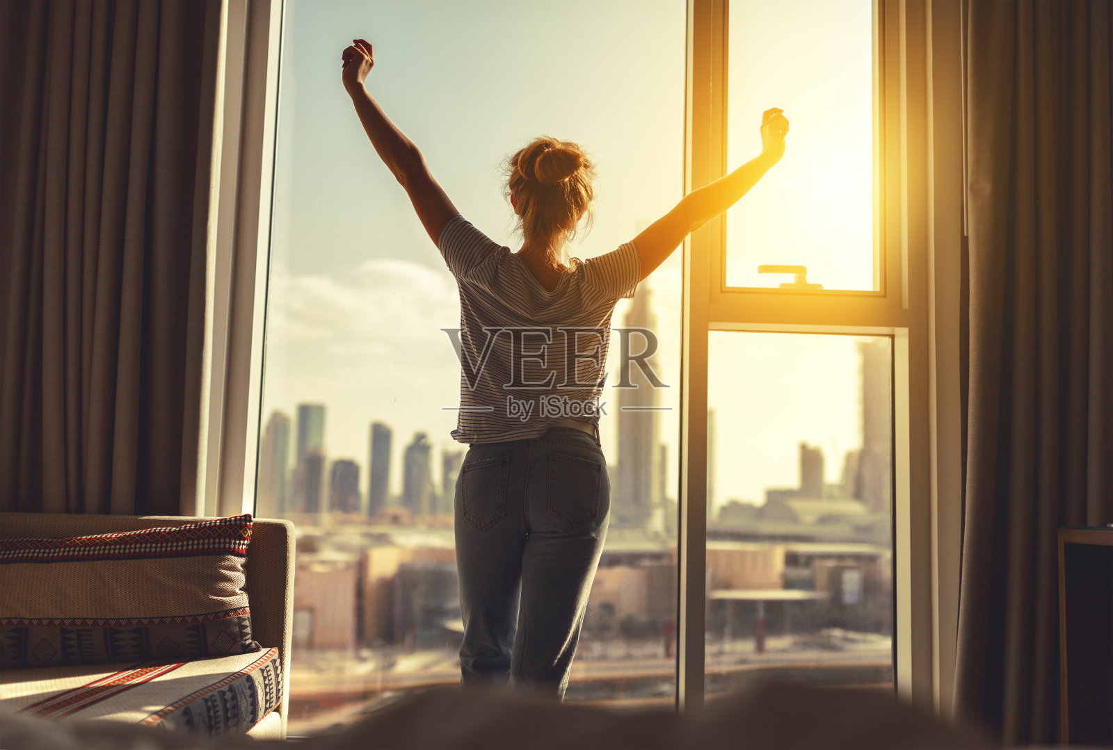 清晨，快乐的女人在窗前伸懒腰，拉开窗帘照片摄影图片
