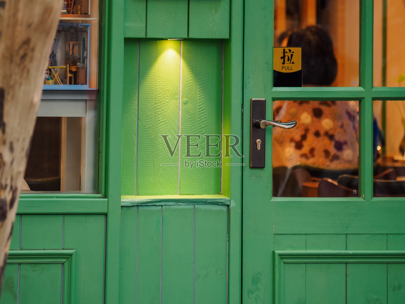 绿色木门，温暖的灯光，门上有“拉”的标志。照片摄影图片