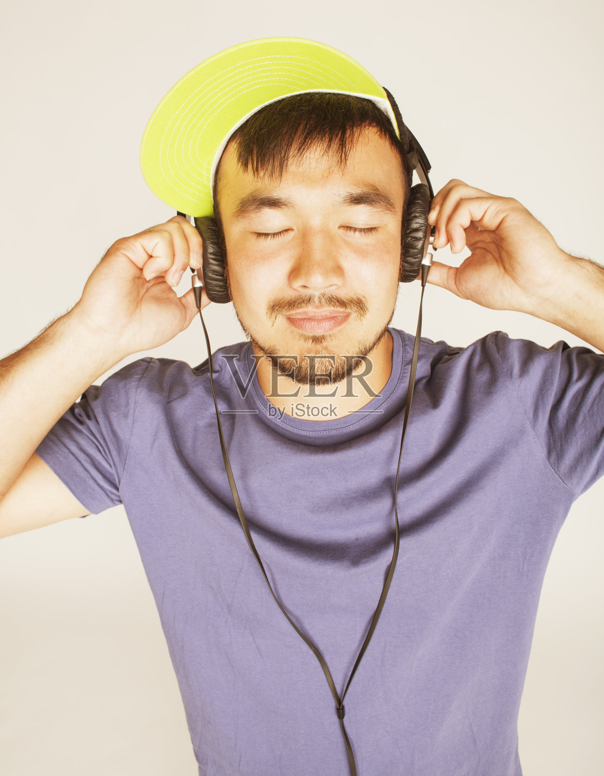 年轻的亚洲人戴着帽子和耳机听音乐照片摄影图片