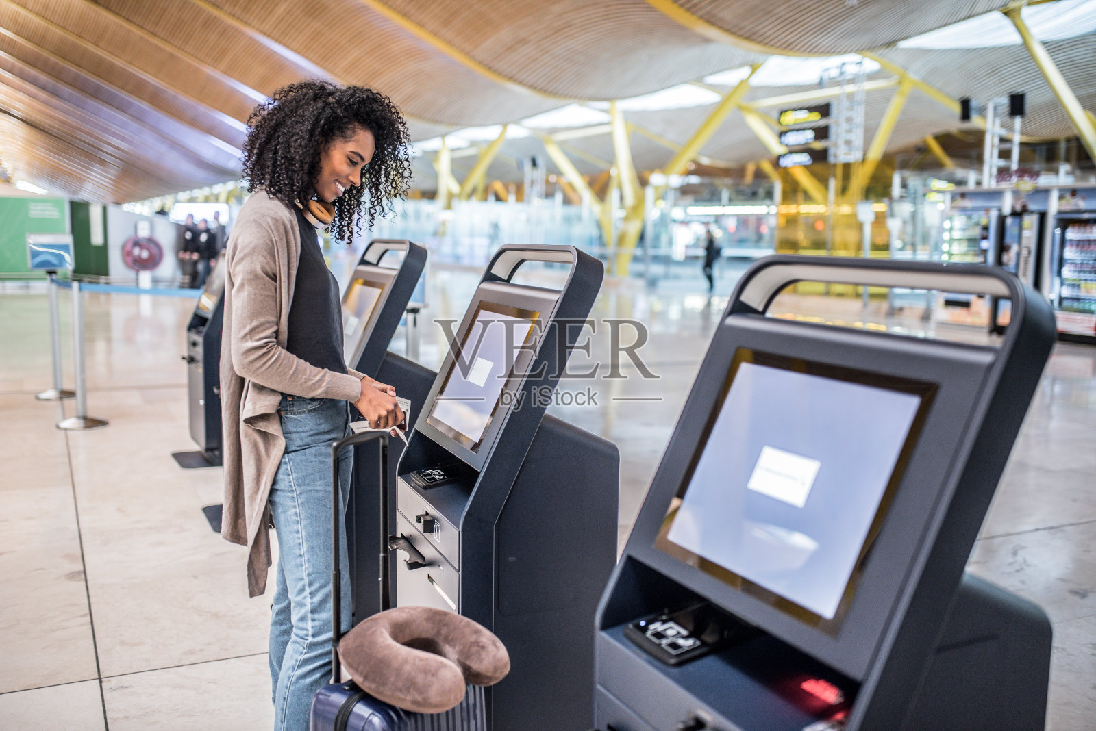 快乐的女人在机场的值机机上拿登机牌。照片摄影图片