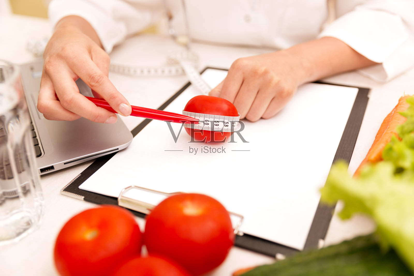 蔬菜饮食营养或药物概念。女营养医生拿着蔬菜和卷尺放在桌上照片摄影图片