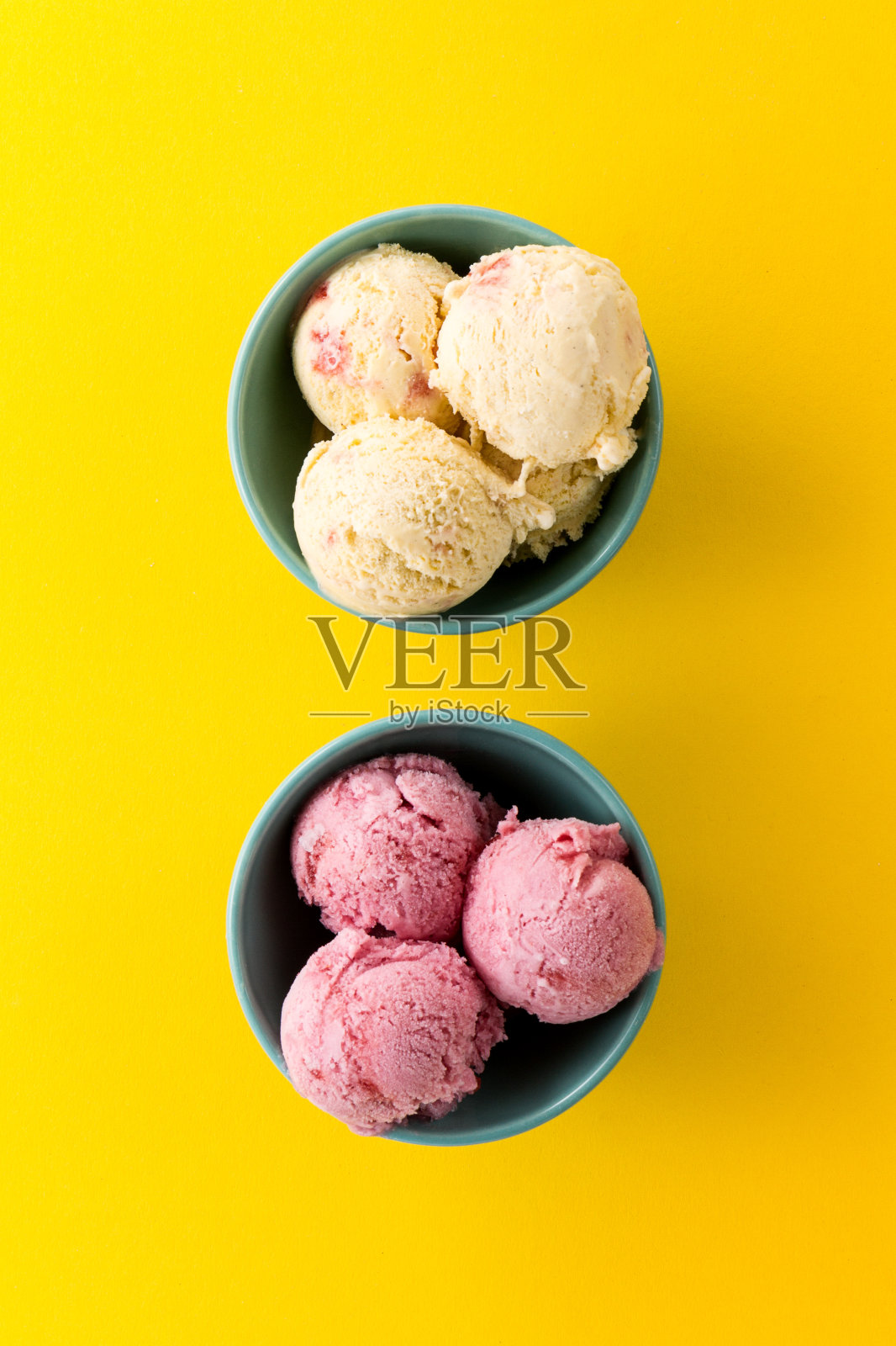 美味的冰淇淋香草草莓勺在蓝色的碗在黄色鲜艳的背景。前视图。照片摄影图片