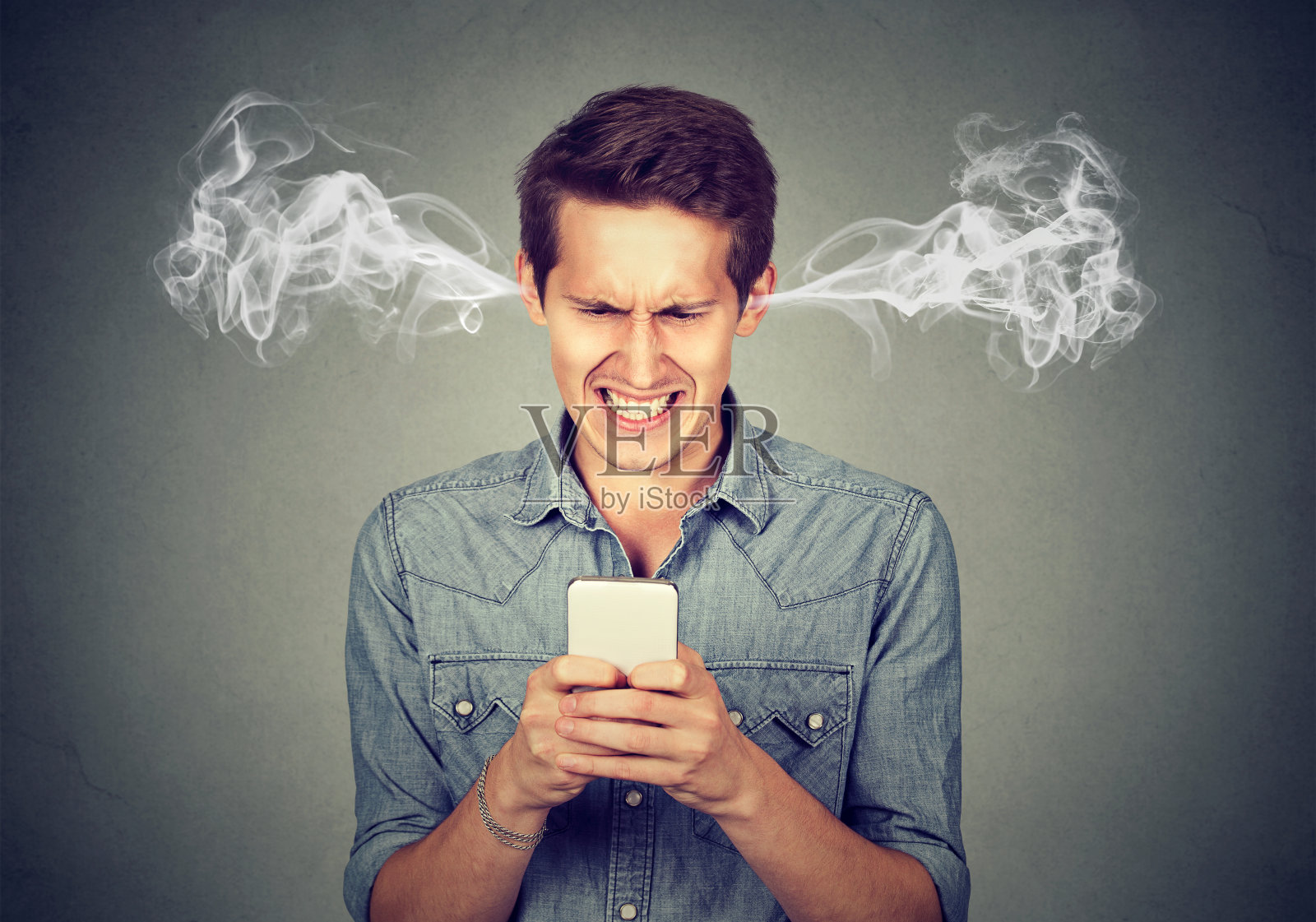 沮丧愤怒的男子在他的智能手机上读短信吹蒸汽出来的耳朵照片摄影图片