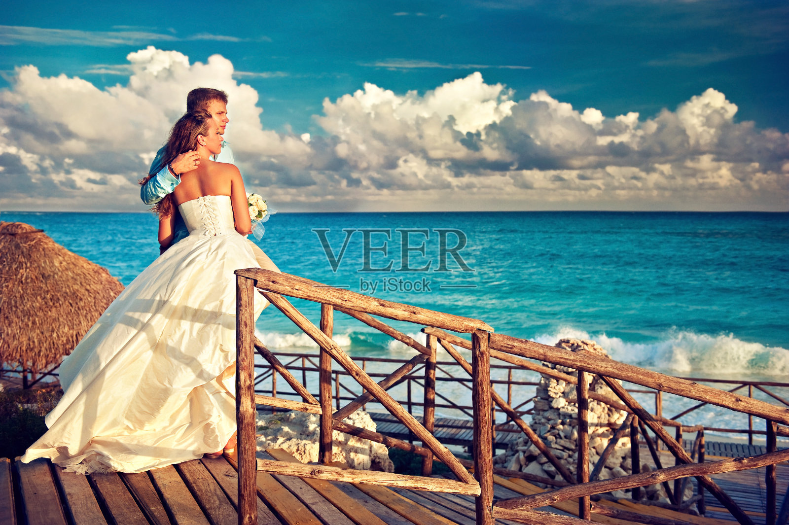 新娘和新郎拥抱在美丽的海景前。在海滩上举行婚礼。照片摄影图片