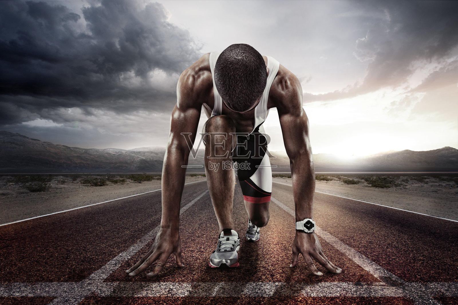 运动背景。短跑运动员在起跑线上的跑道前戏剧性的腾空而起。照片摄影图片