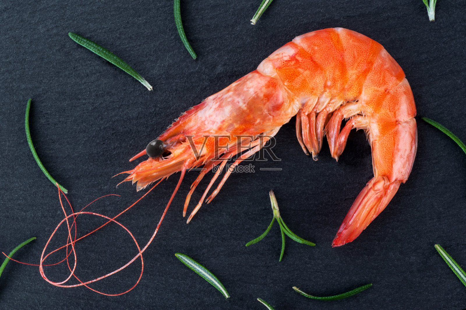 用迷迭香煮熟的大虾放在深色的背景上。照片摄影图片