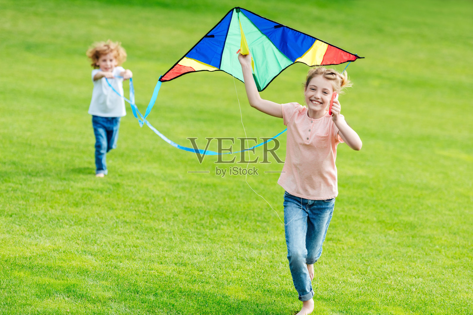 快乐可爱的兄弟姐妹玩风筝，在公园的绿色草坪上奔跑照片摄影图片