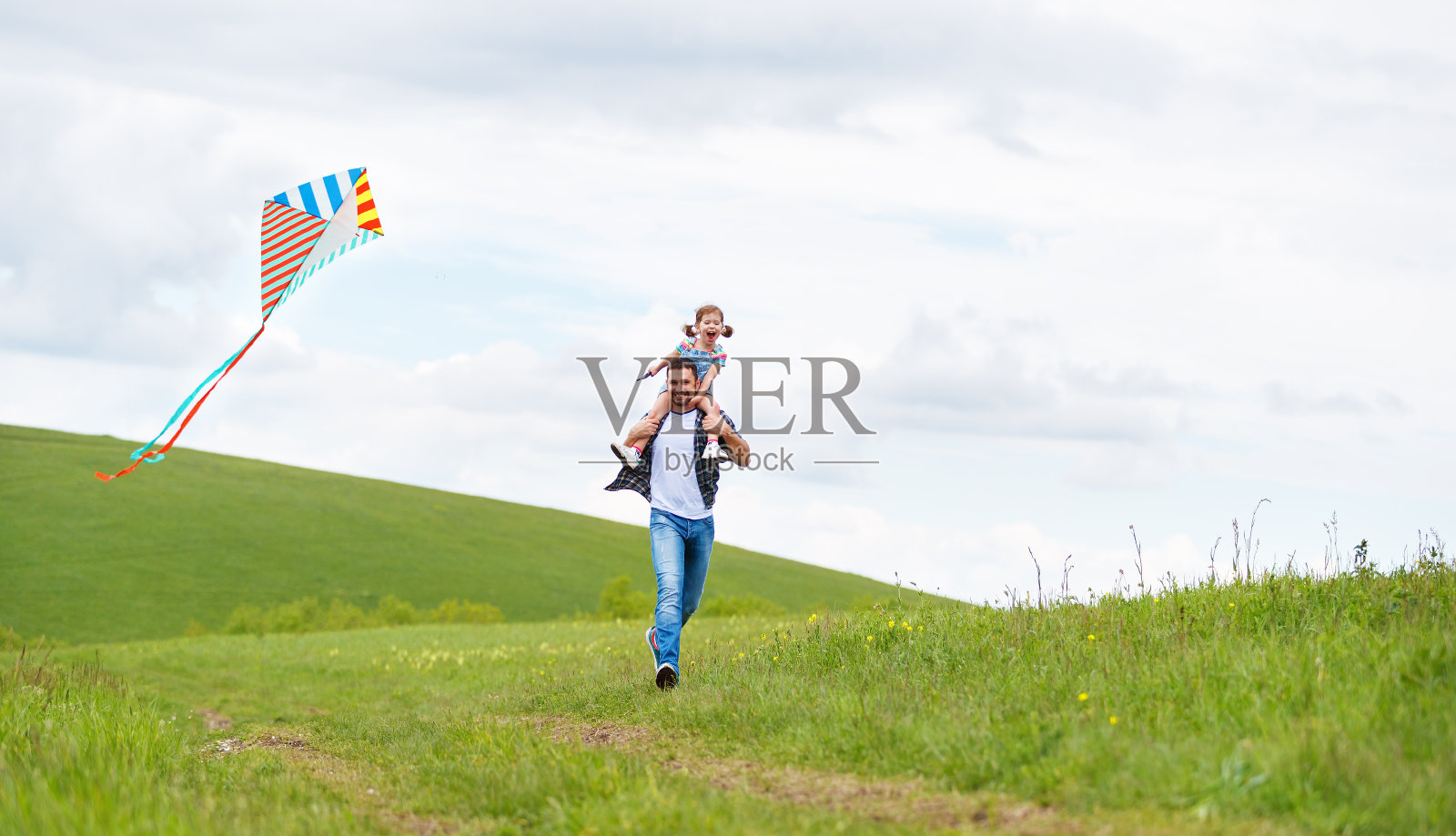 幸福的家庭父亲和小女儿在草地上追风筝照片摄影图片