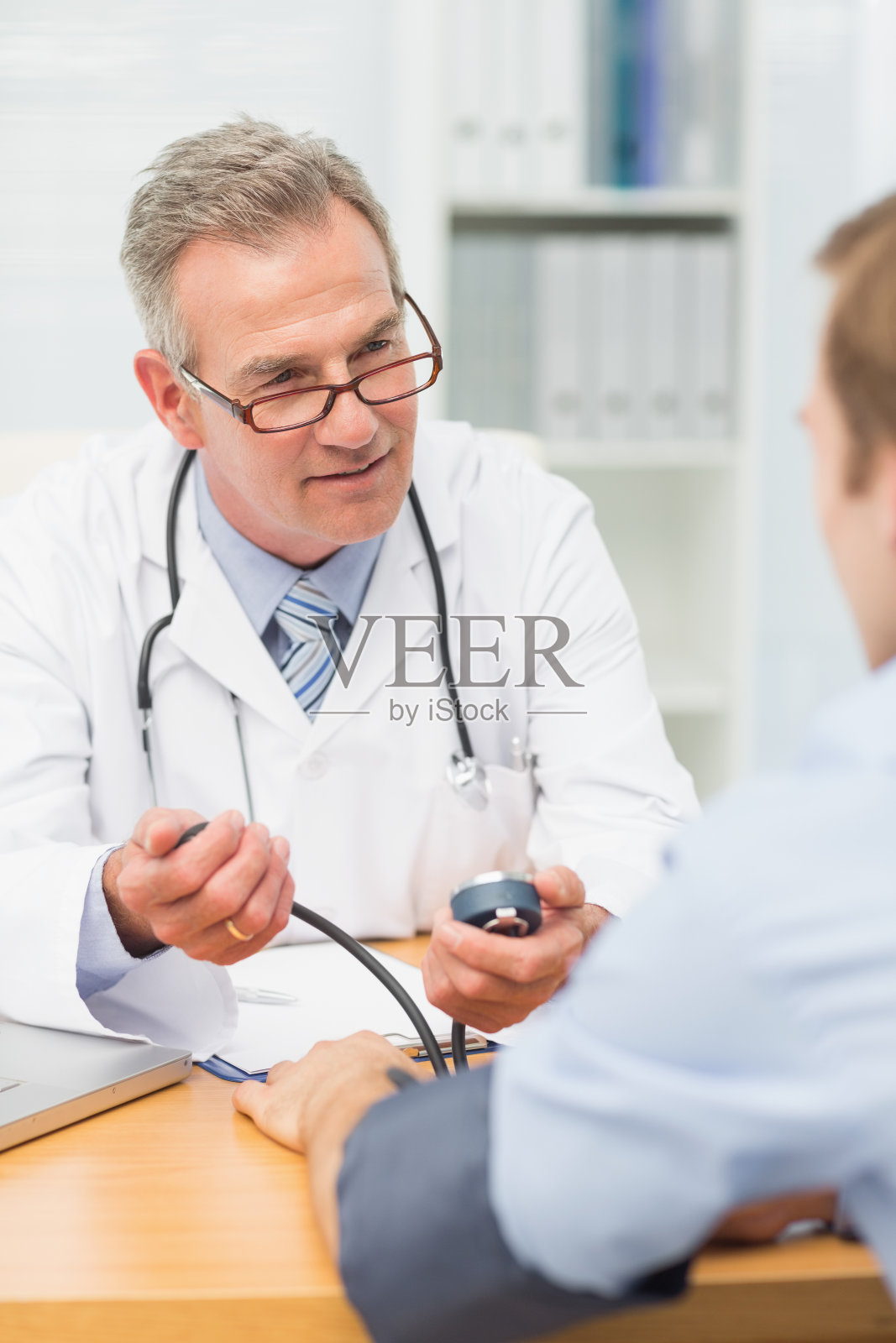 微笑成熟的医生给他的病人量血压照片摄影图片