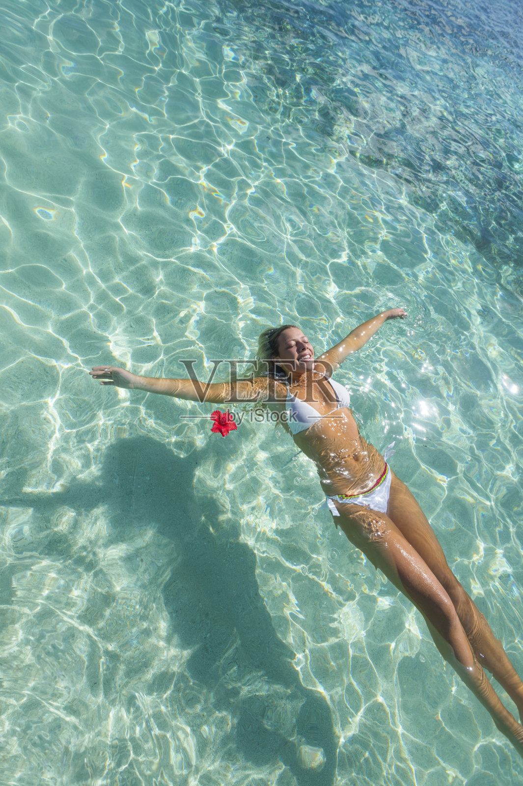 在热带海滩碧绿的水面上漂浮的女人。照片摄影图片