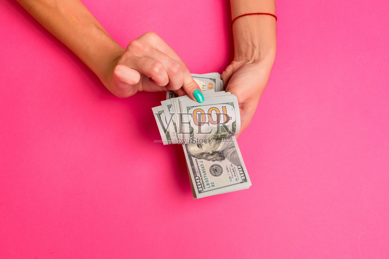 一个女人手里拿着钱。粉红色的背景。俯视图拷贝空间照片摄影图片