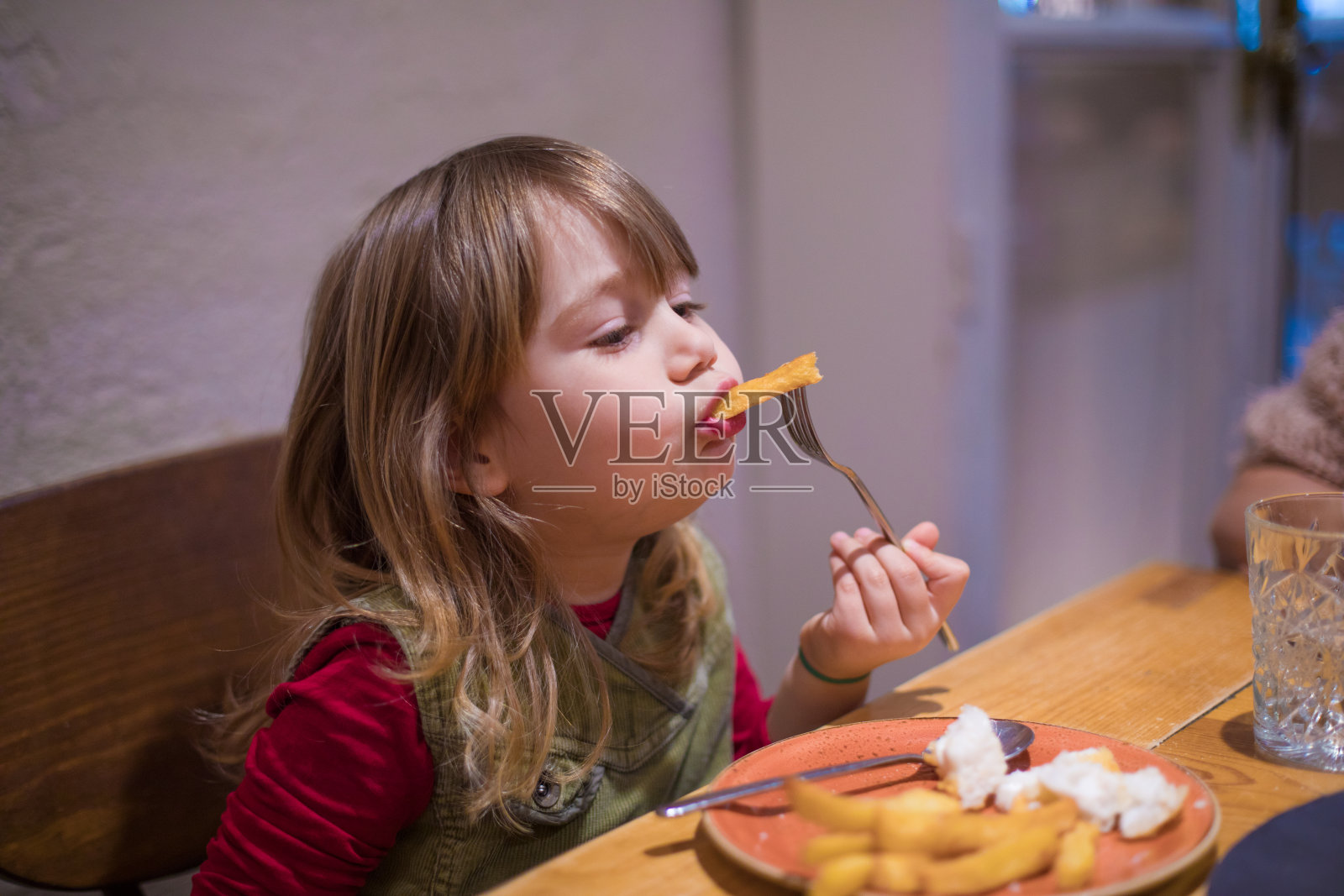 小女孩用叉子吃薯条照片摄影图片