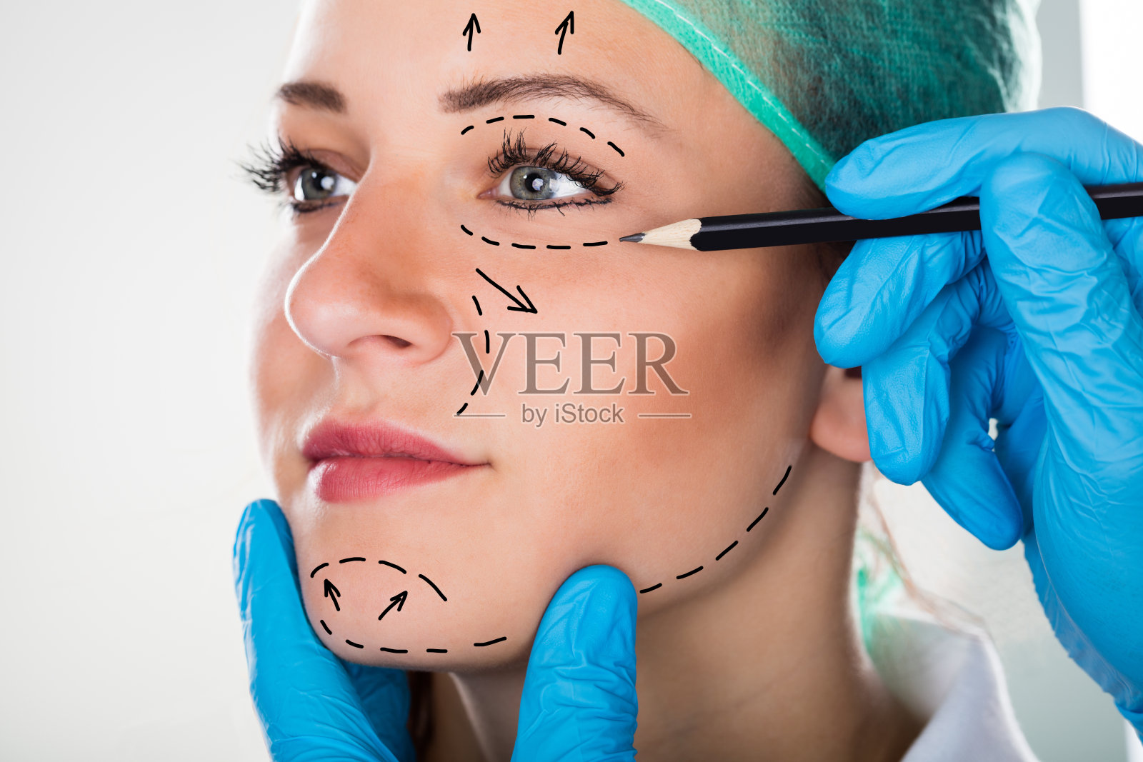 外科医生在妇女脸上画线做整形手术照片摄影图片