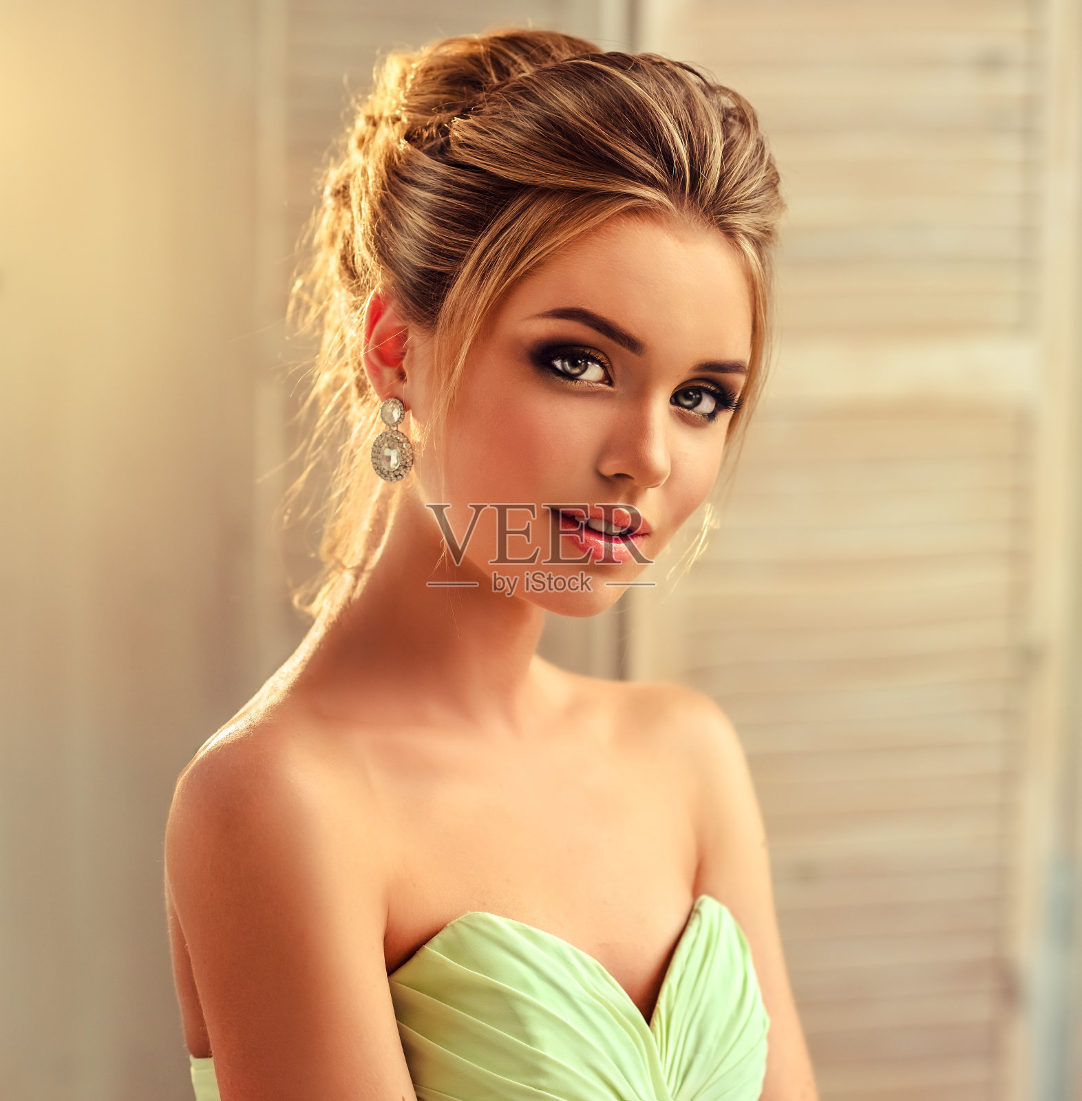 年轻迷人的金发模特穿着晚礼服，戴着珠宝耳环。照片摄影图片