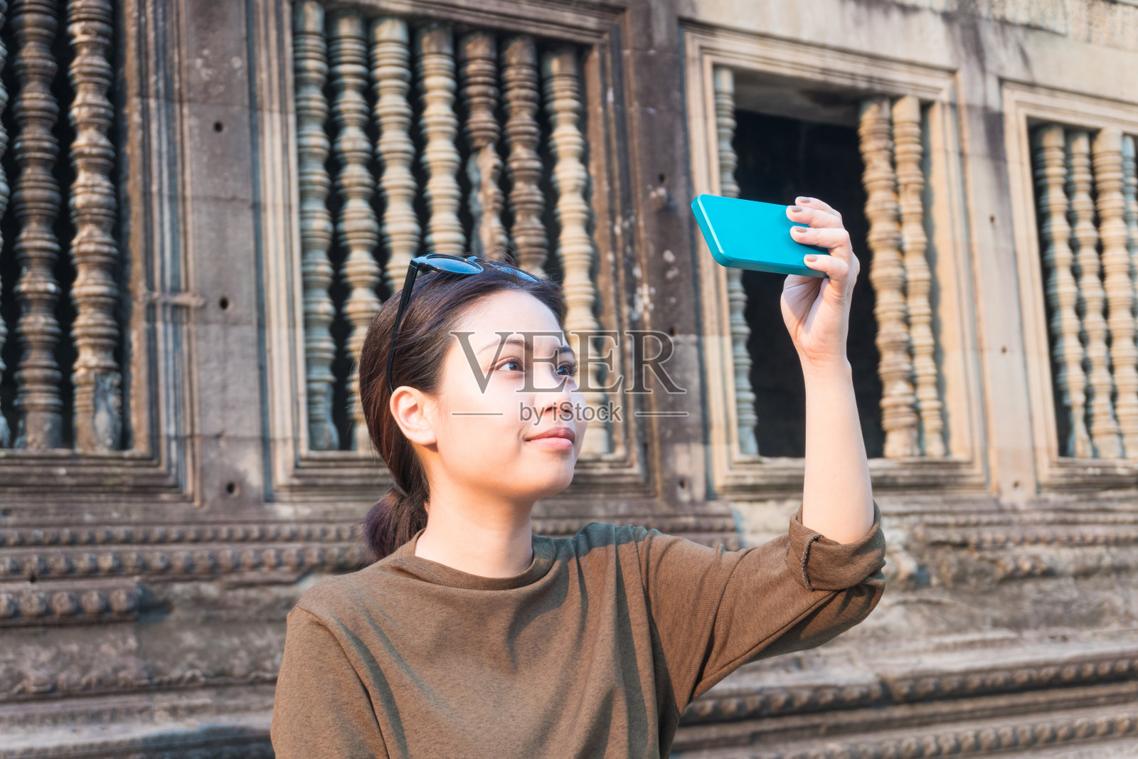 在柬埔寨吴哥窟，女游客用智能手机自拍照片摄影图片