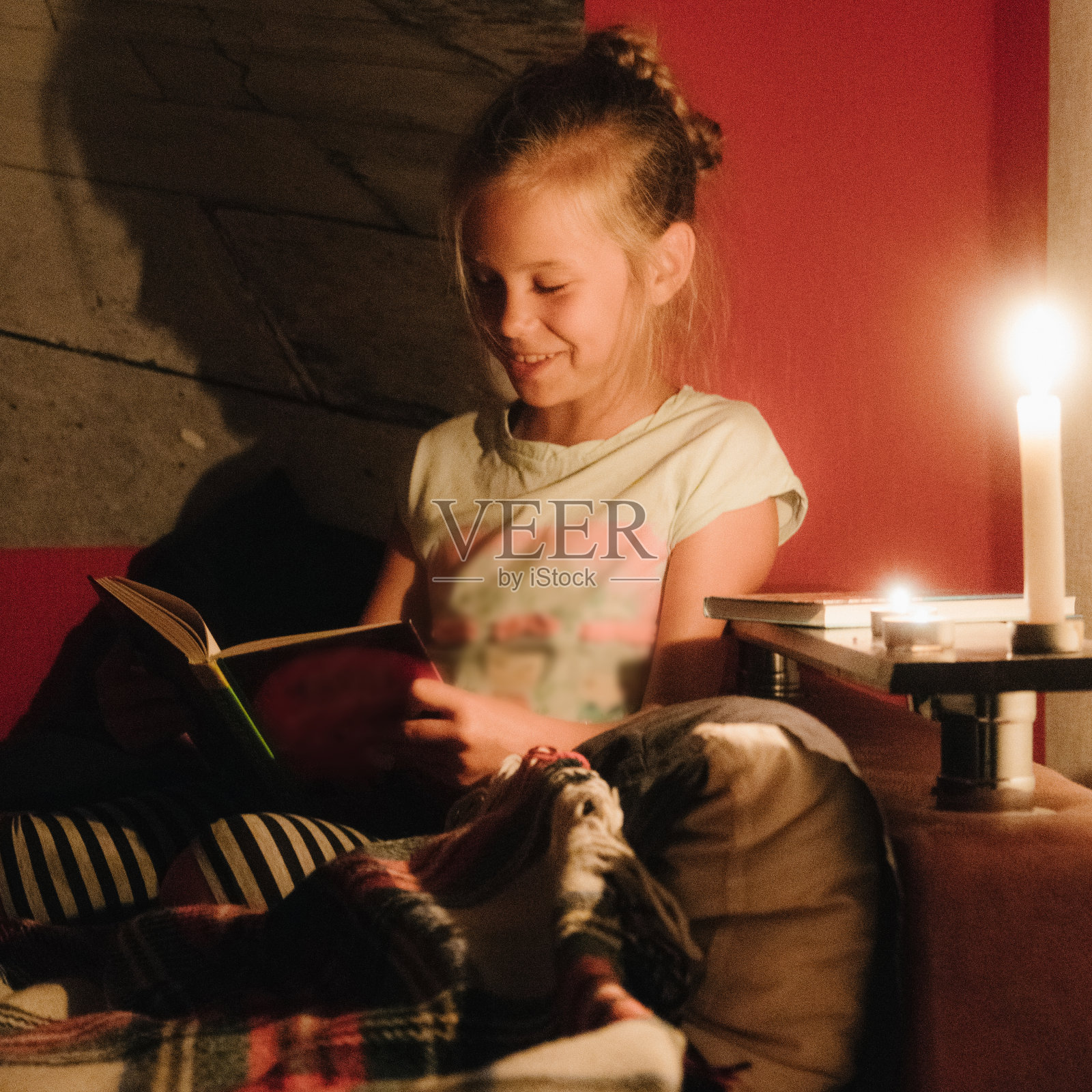 小女孩拿着蜡烛在床上看书照片摄影图片