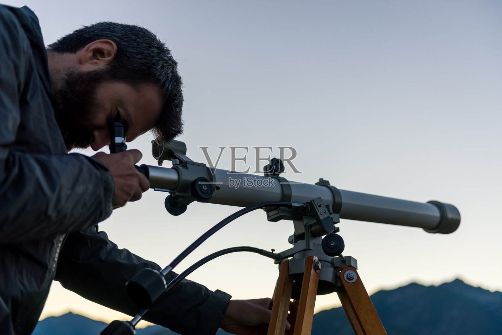 夏日傍晚，在户外的山上，透过望远镜看山顶的人照片摄影图片