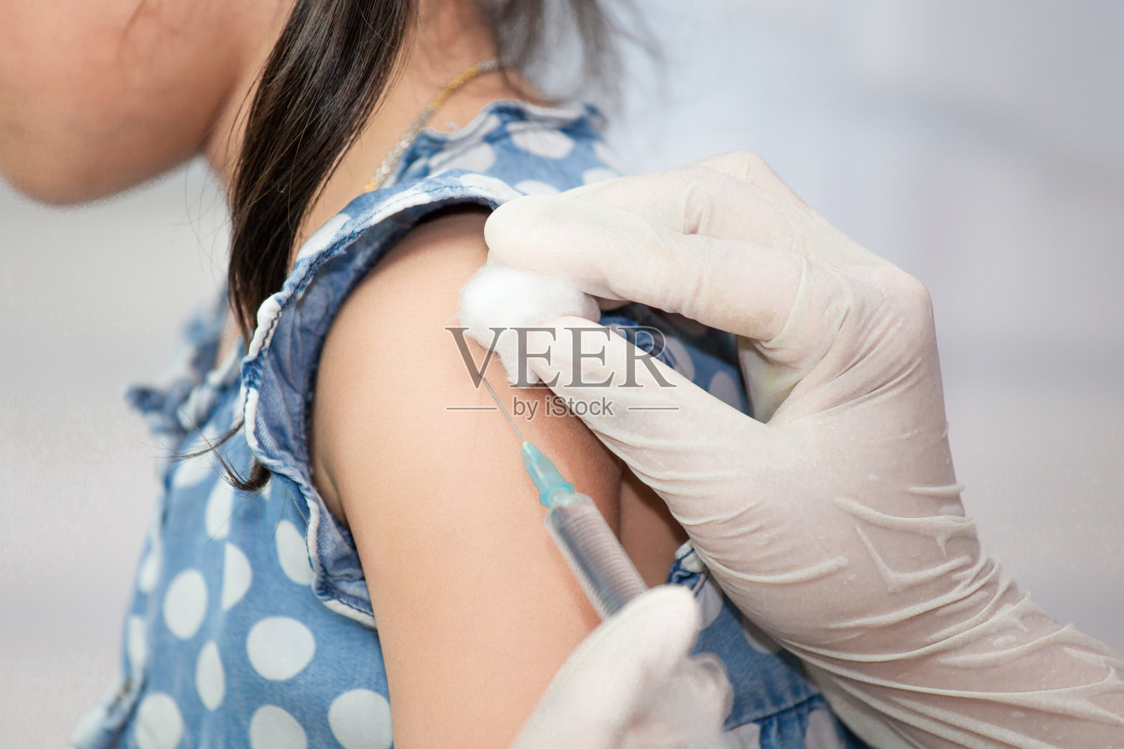 医生在亚洲小女孩的手臂注射疫苗照片摄影图片