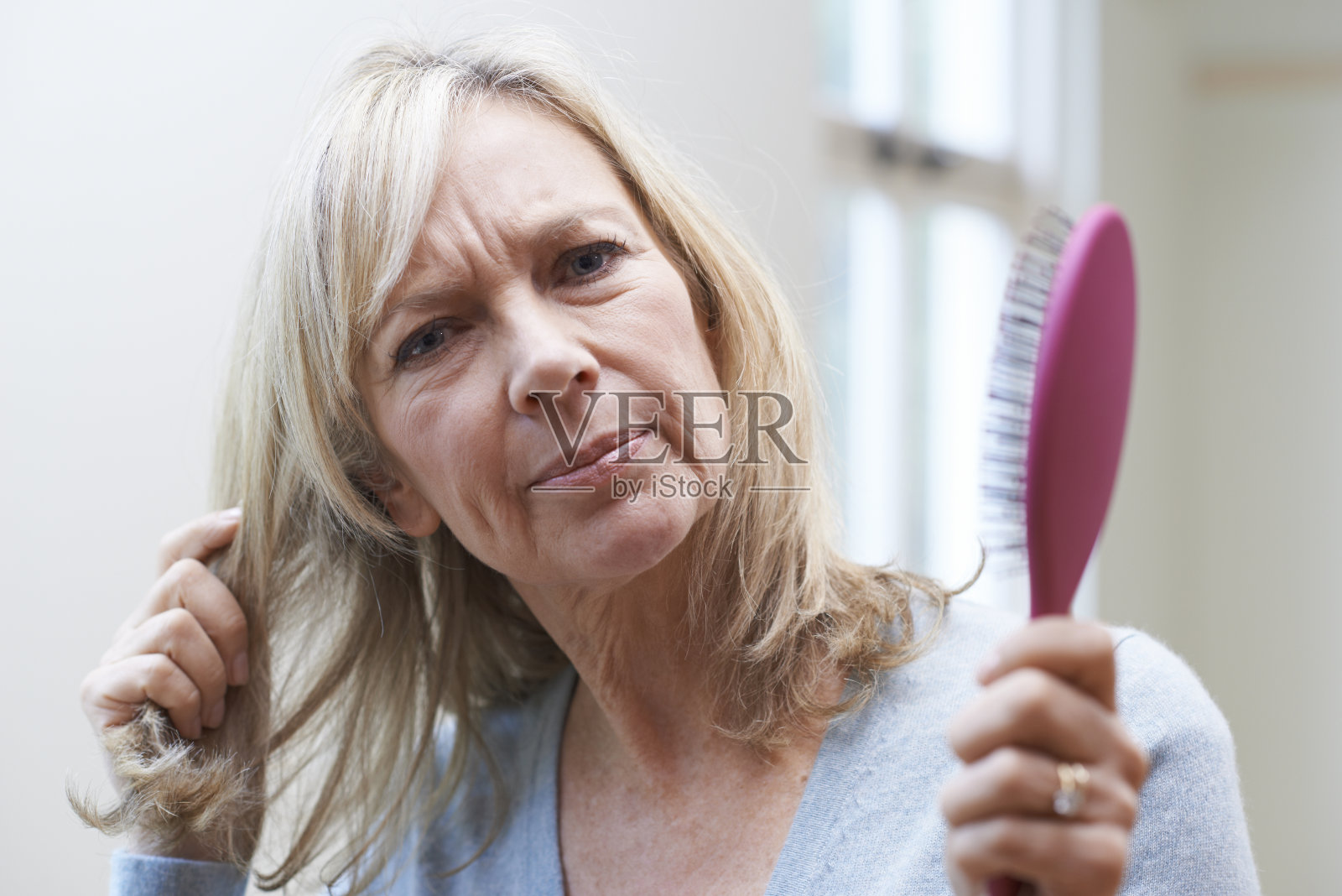 成熟的女人用梳子担心脱发照片摄影图片