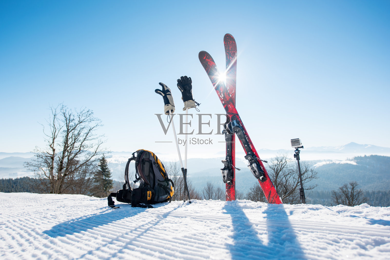 拍摄滑雪装备-滑雪板，背包，棍棒，手套和行动相机在单脚架上，在滑雪胜地的滑雪坡上的冬季运动生活方式极端活跃的概念照片摄影图片