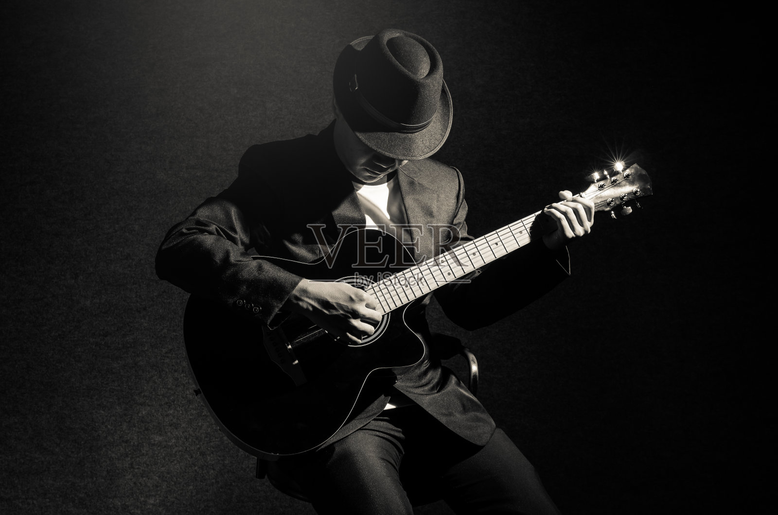 音乐家在黑色背景下弹奏吉他，音乐理念照片摄影图片