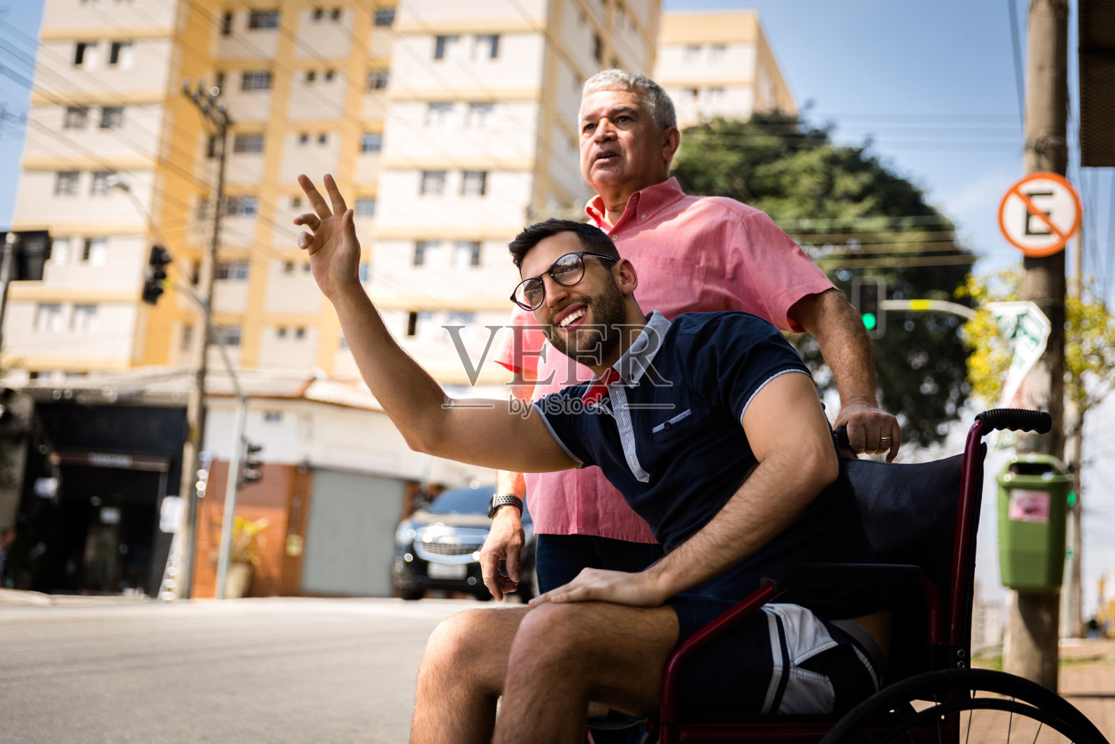 爸爸和他的儿子坐在轮椅上等公共汽车照片摄影图片