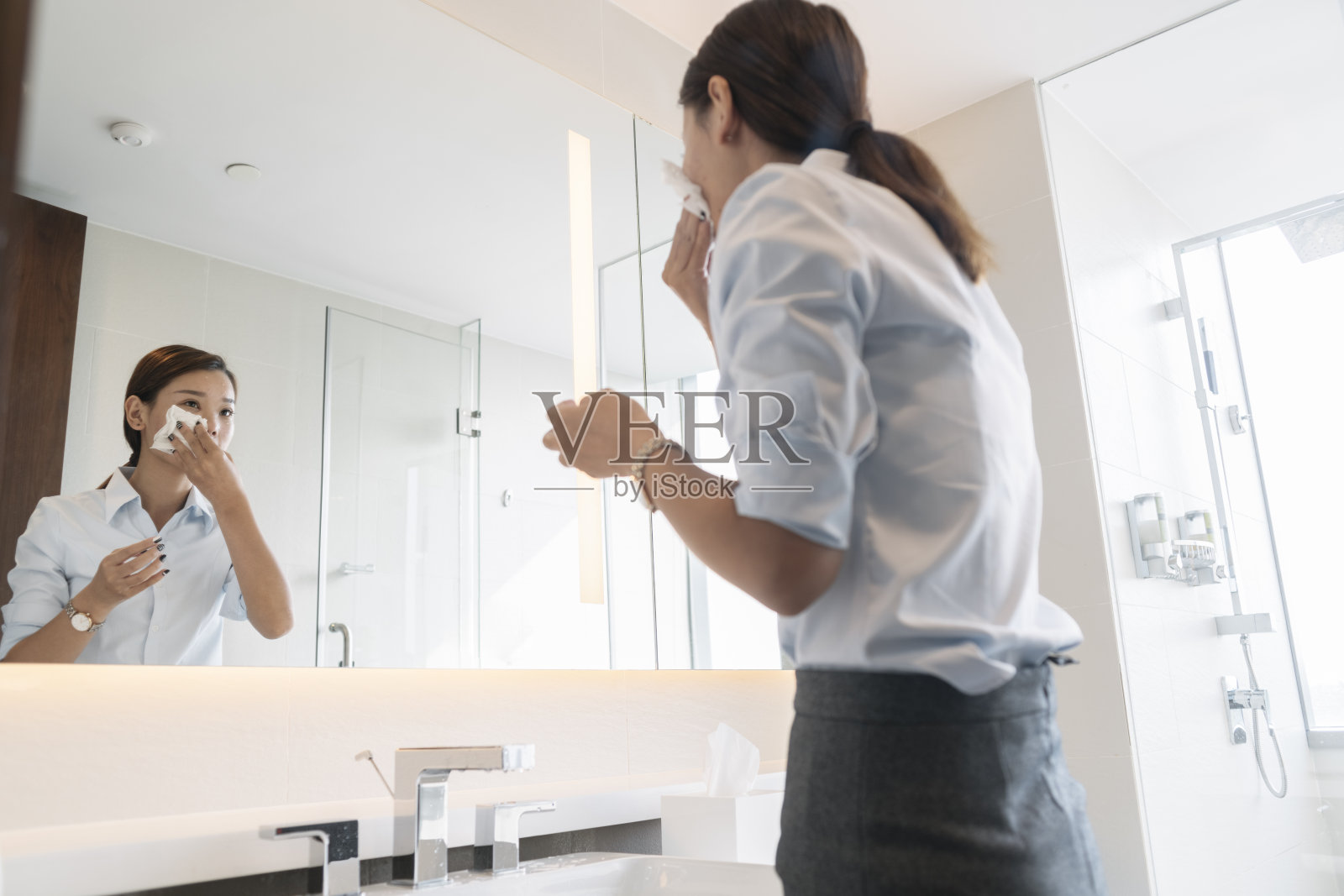 浴室里一个看着镜子的女人照片摄影图片