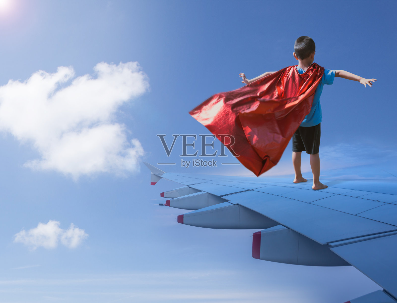 男孩打扮成超级英雄站在飞机机翼上照片摄影图片