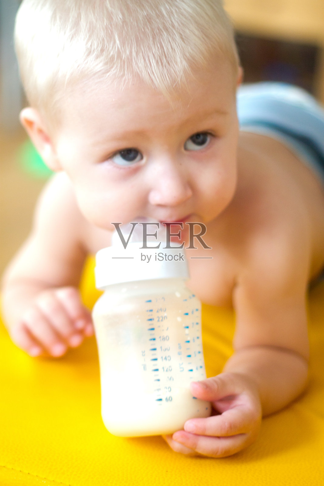金发小孩用奶瓶喝婴儿配方奶粉照片摄影图片