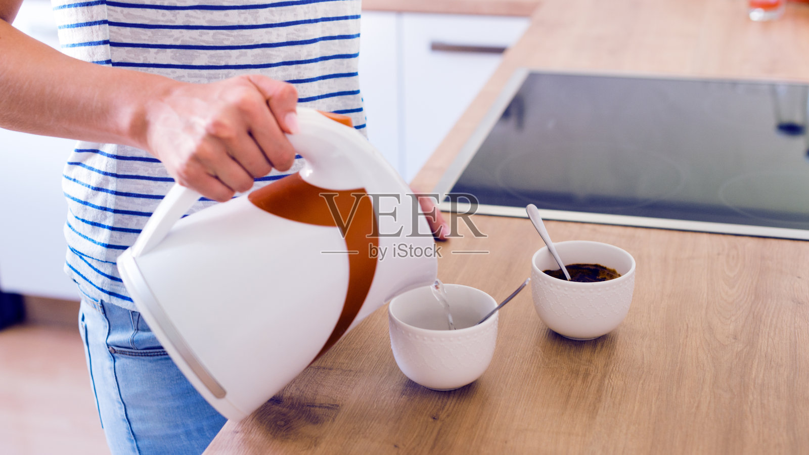 不认识的女人在煮土耳其咖啡。把水倒进杯子里。照片摄影图片