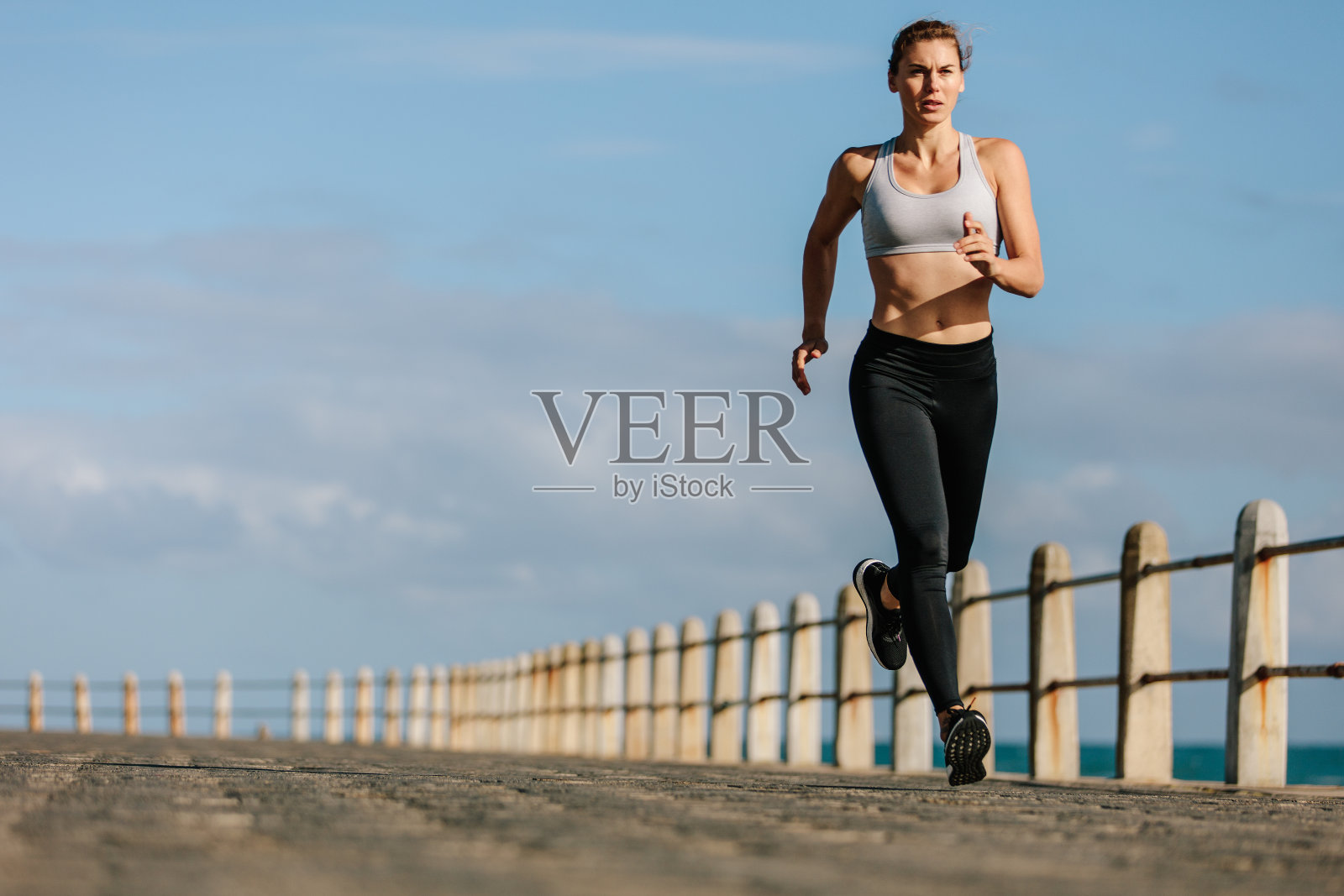 女运动员在海边的一条路上跑步照片摄影图片