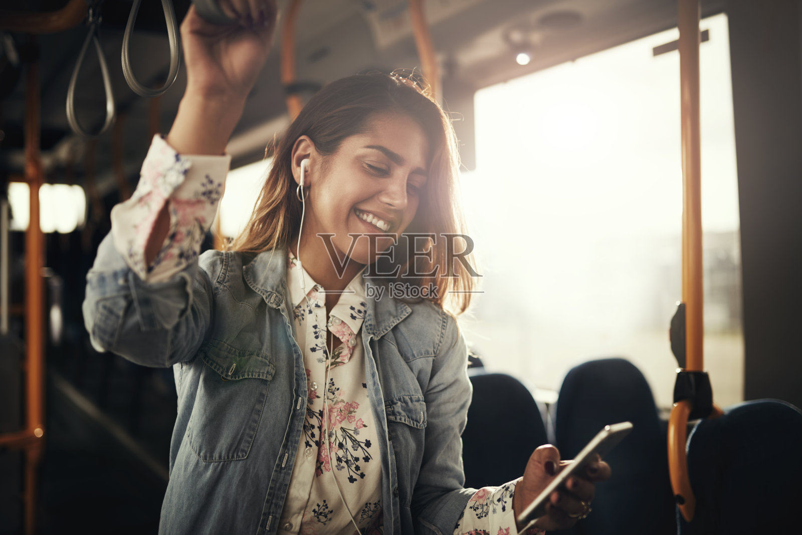微笑的年轻女子坐在公共汽车上听音乐照片摄影图片