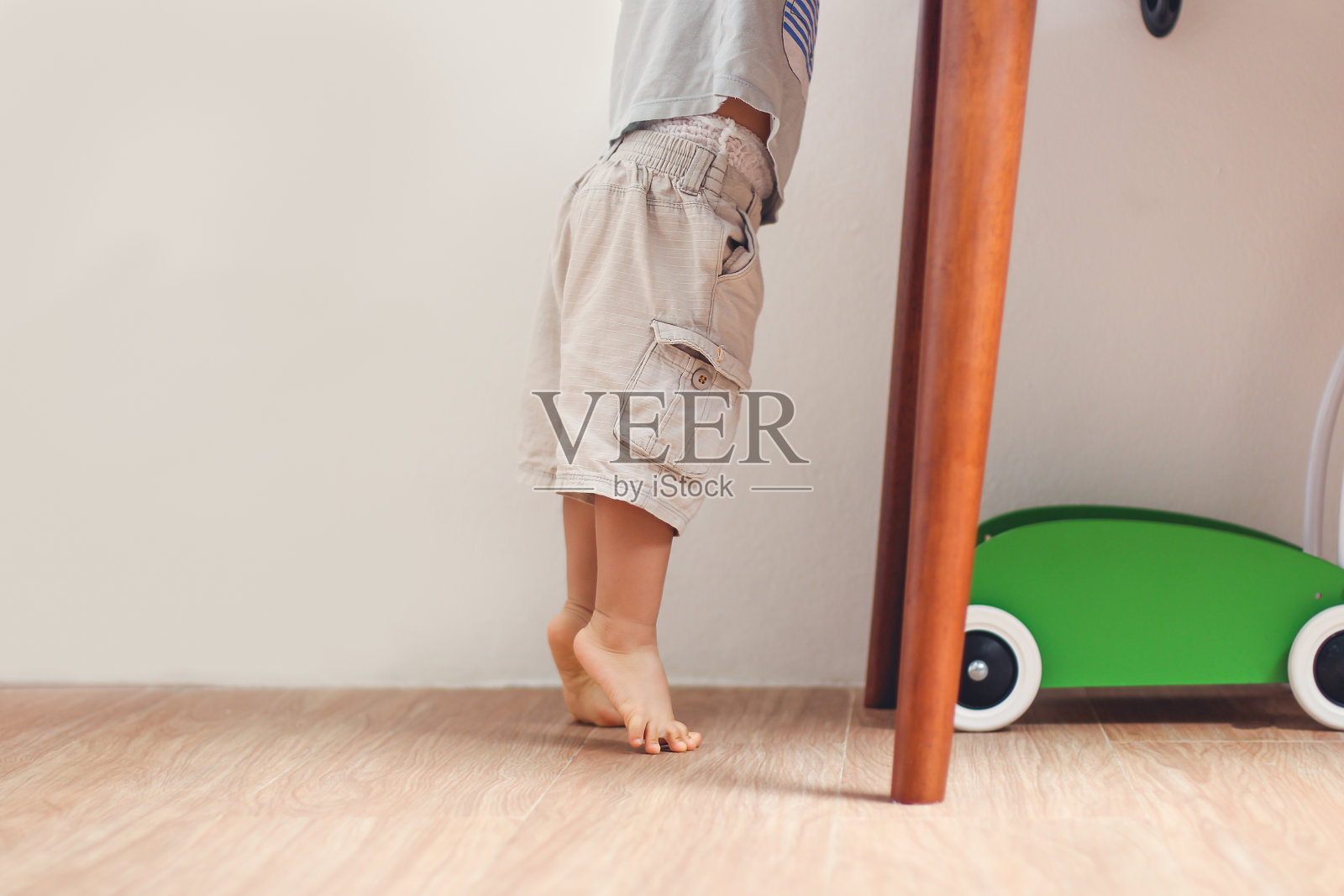 亚洲18个月/ 1岁蹒跚学步的婴儿男孩踮着脚尖站在家里的地板上的特写照片照片摄影图片