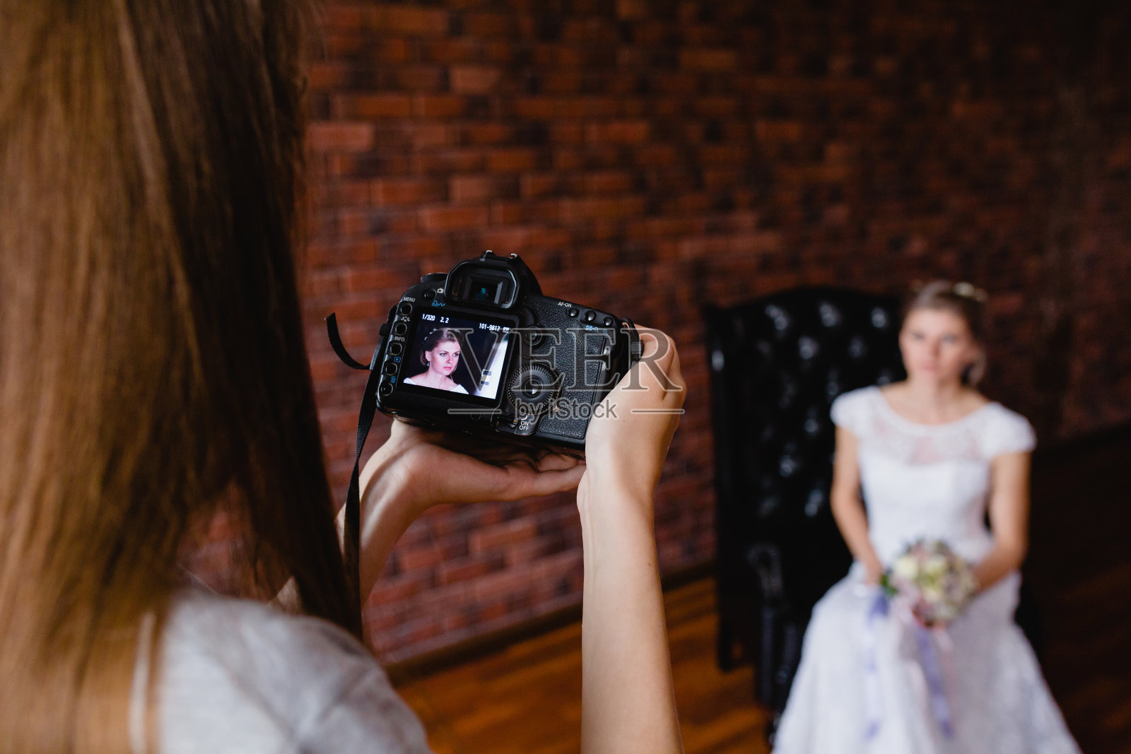 摄影师在工作室里的一张大皮椅上给新娘拍照照片摄影图片