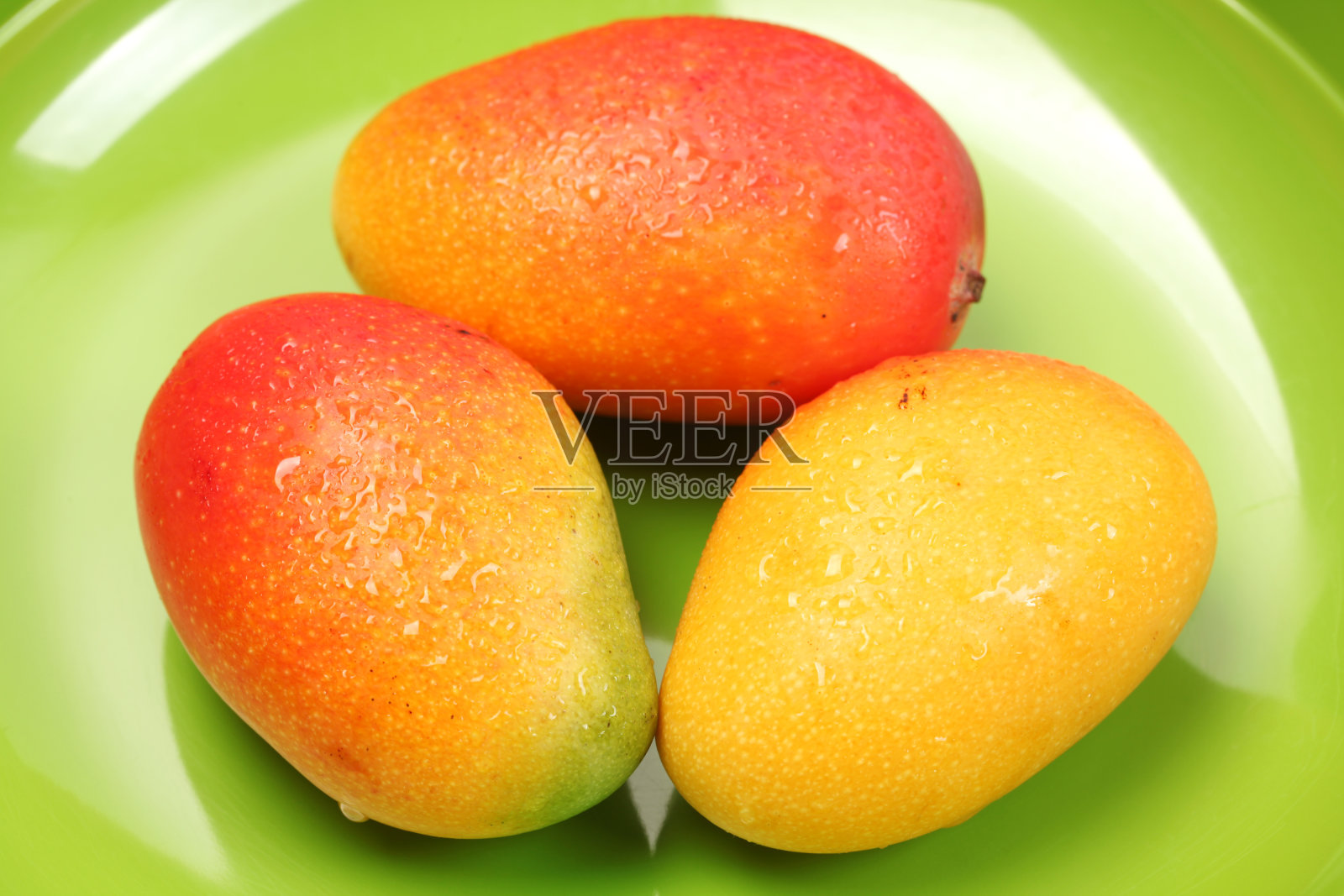 新鲜成熟的芒果放在绿色的盘子里照片摄影图片