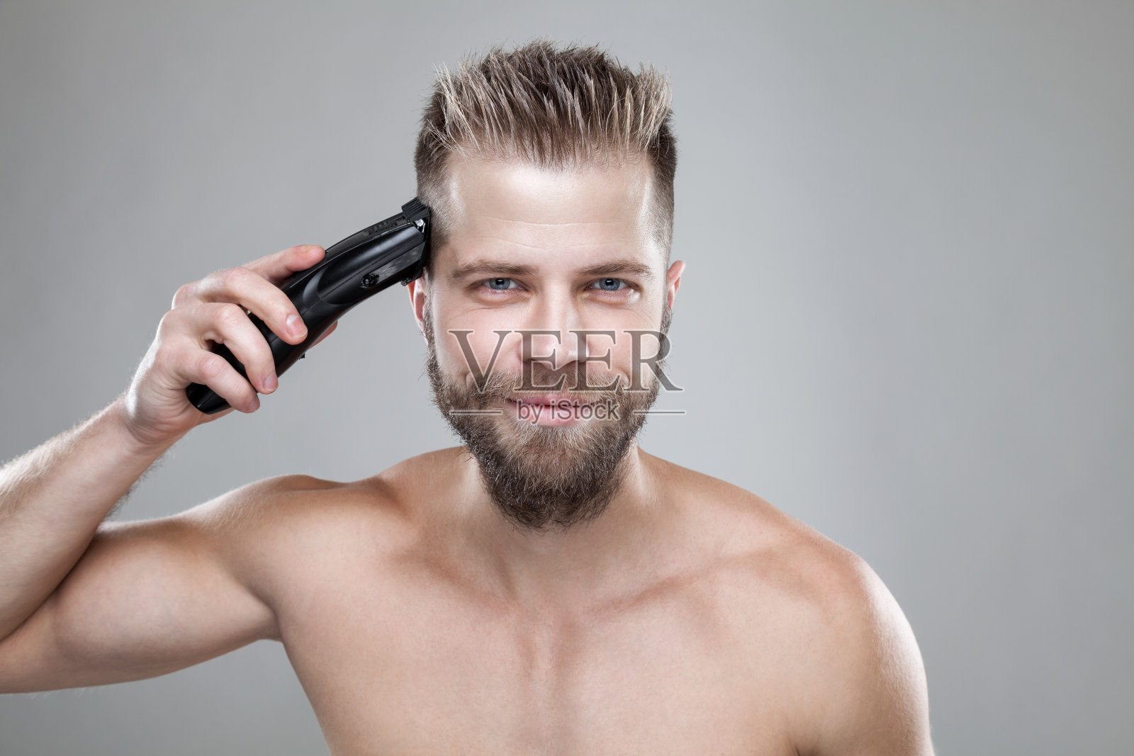 英俊的男人用剪子剪自己的头发照片摄影图片