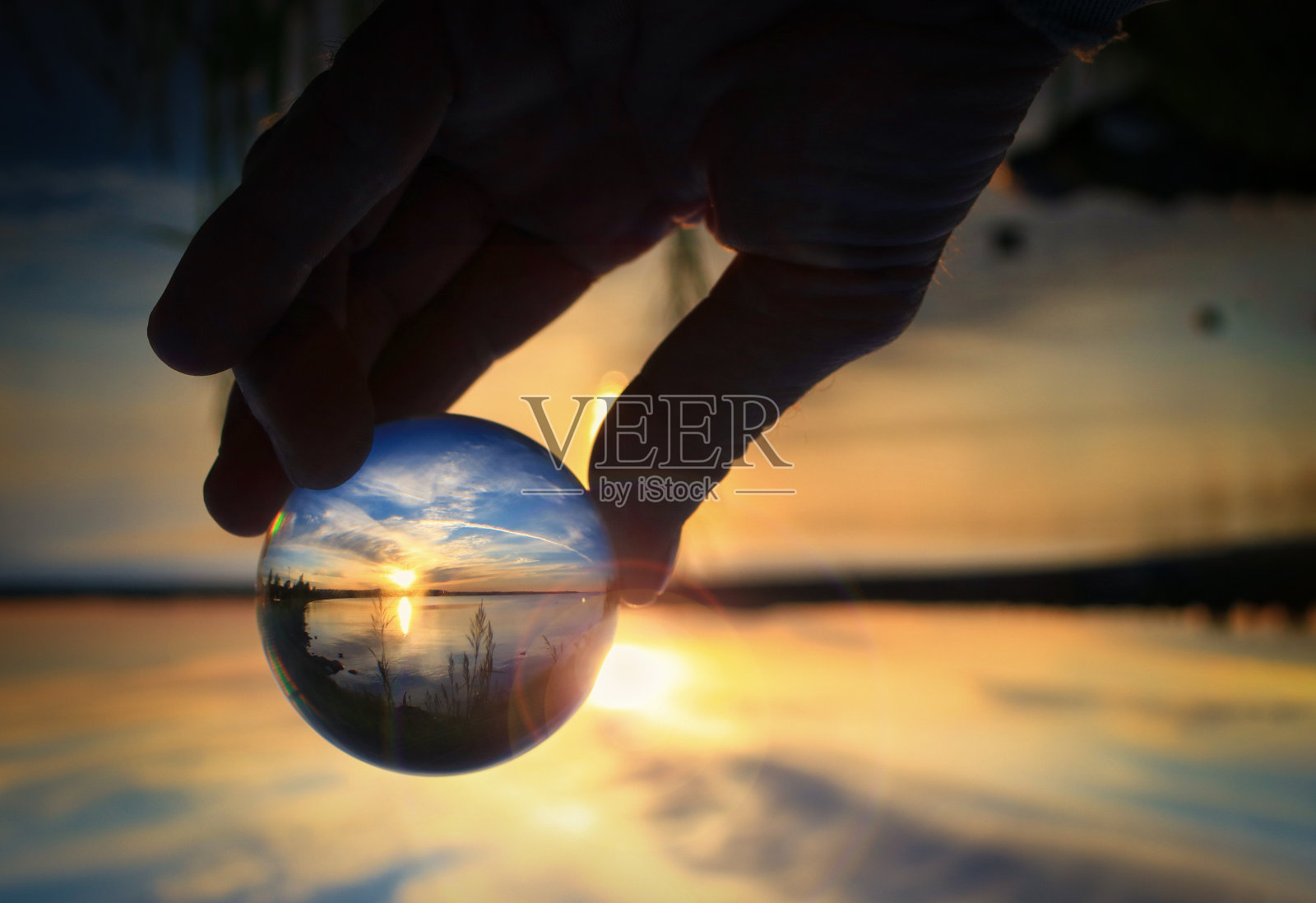 湖面上倒映着日落的透明玻璃球照片摄影图片