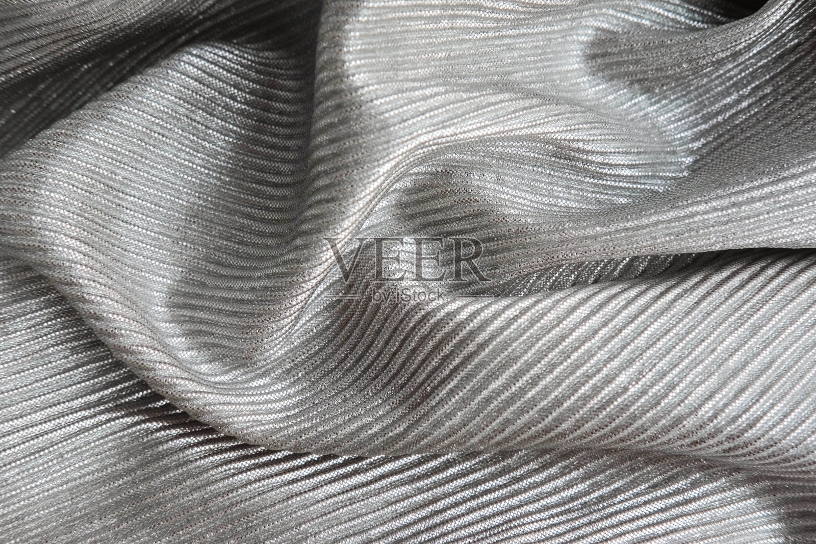 压纹闪亮的织物，打褶。银纺织材料。照片摄影图片