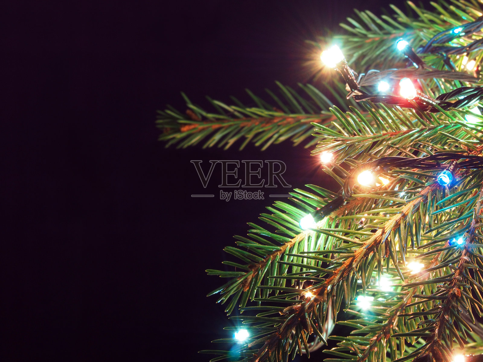 在黑暗的背景上装饰着发光的花环的圣诞树照片摄影图片
