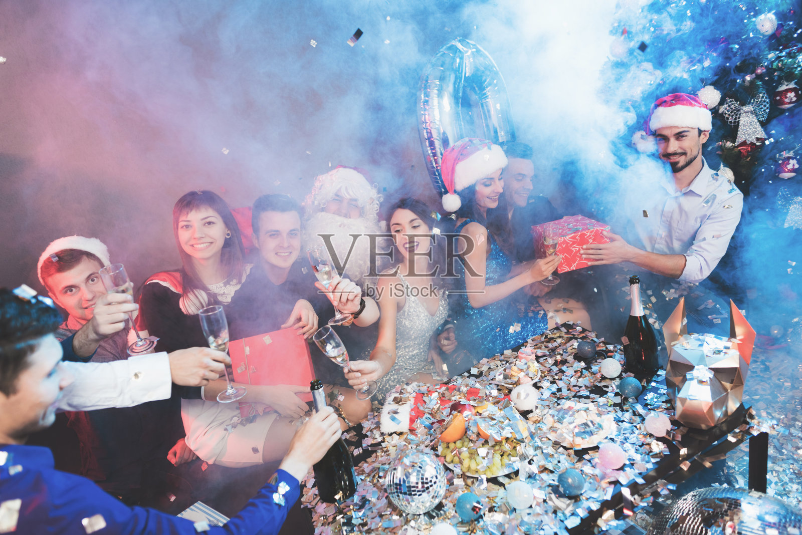 新年晚会上大家欢天喜地。人们喝香槟，交换礼物。照片摄影图片