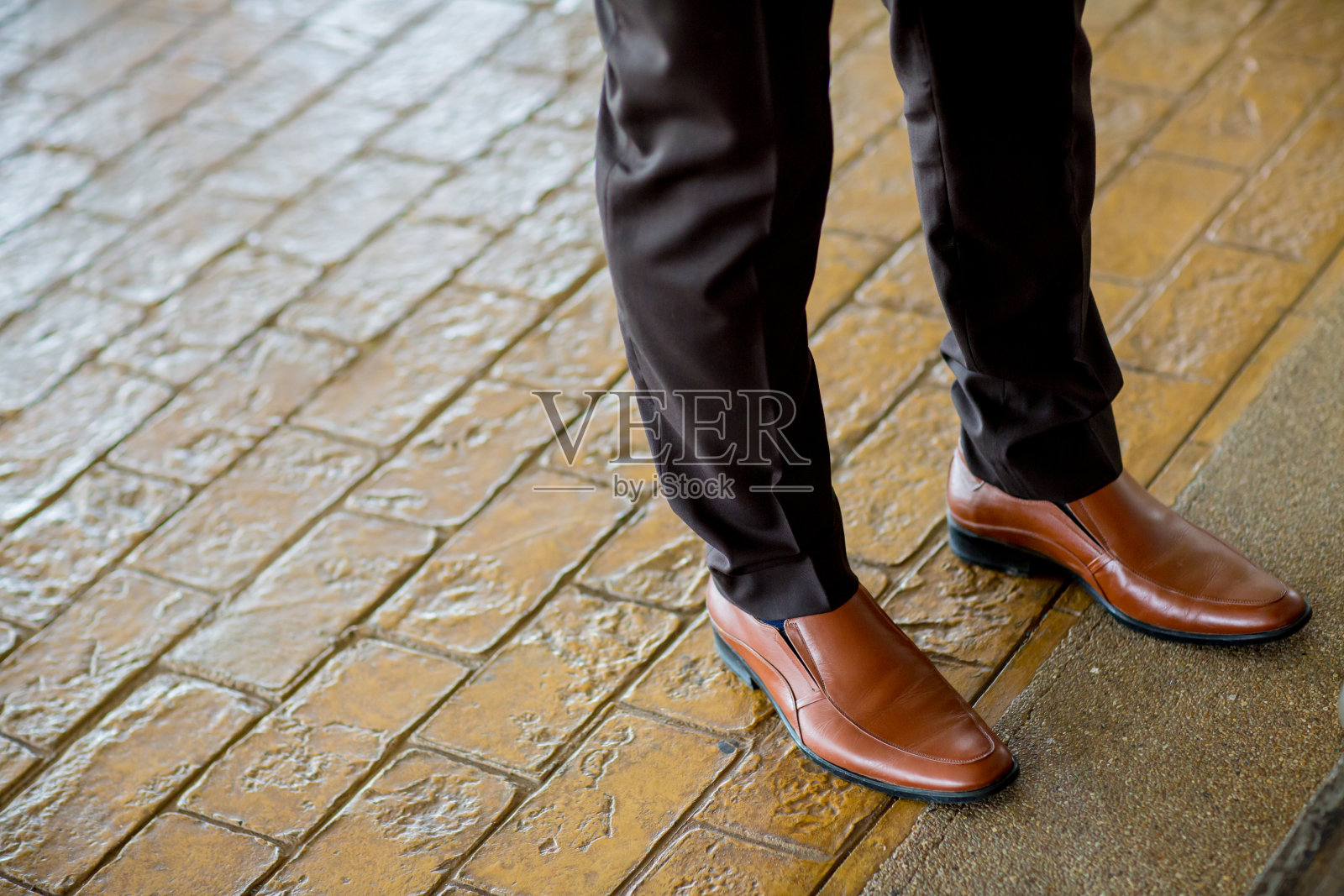 嬉皮士时尚男子的腿在黑色牛仔裤和棕色皮靴在木地板上照片摄影图片