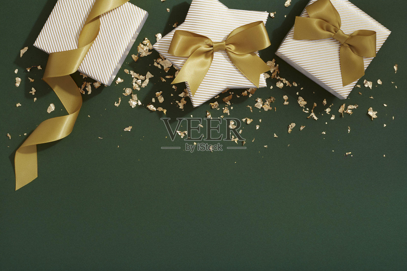 圣诞礼物和金色的丝带在深绿色的背景上，平躺着照片摄影图片