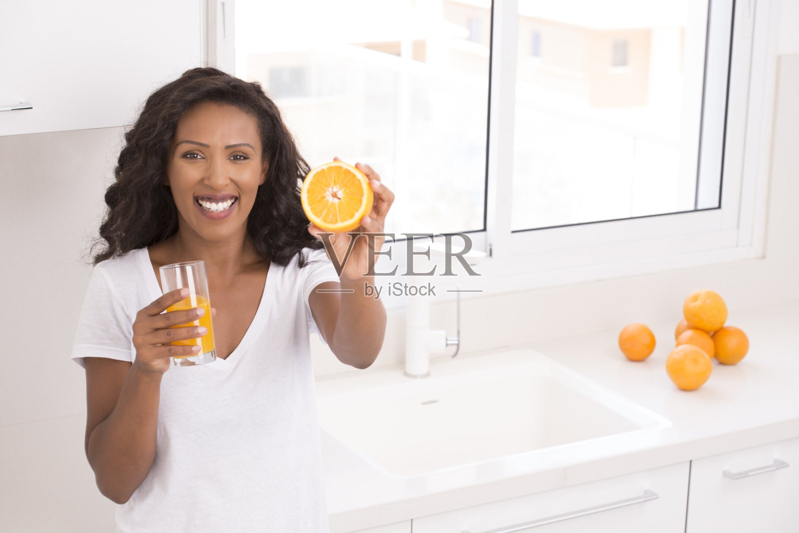 女人展示了一半的橙色水果。橙汁和水果概念。照片摄影图片
