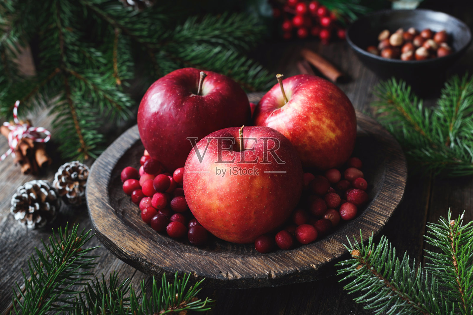 圣诞节的静物画。美味的红色苹果，蔓越莓，坚果，松果和冷杉树枝照片摄影图片