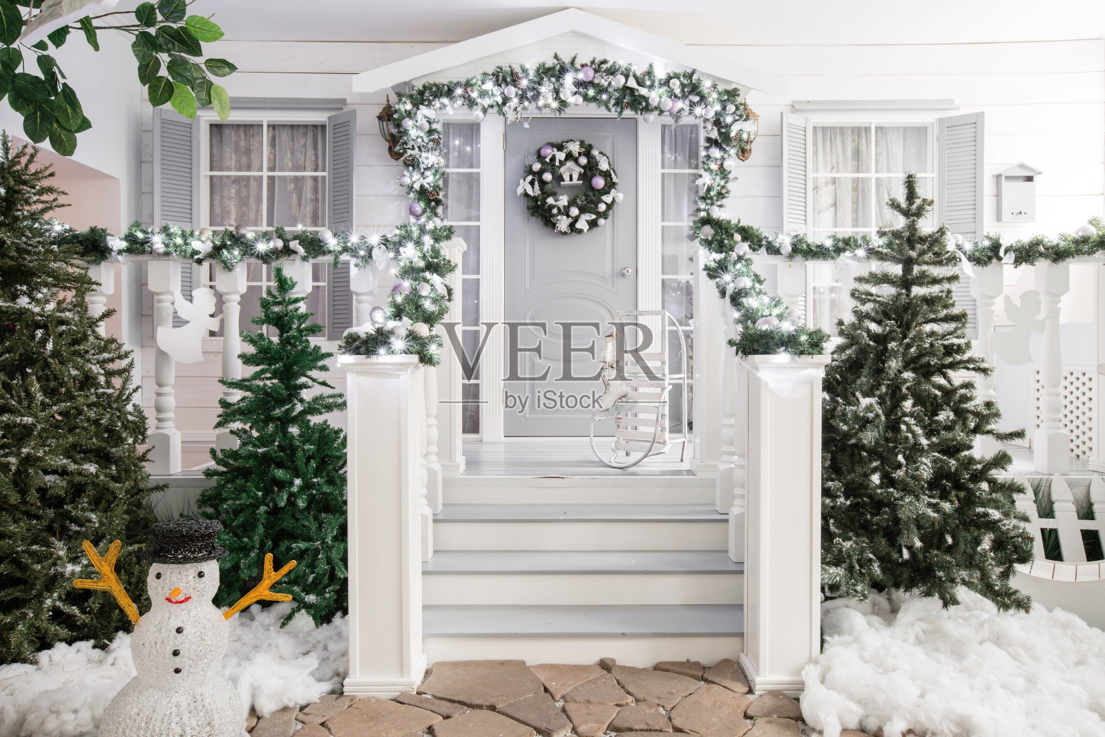 房屋入口为节日装饰。圣诞装饰。栏杆上用冷杉树枝编成的花环和灯照片摄影图片