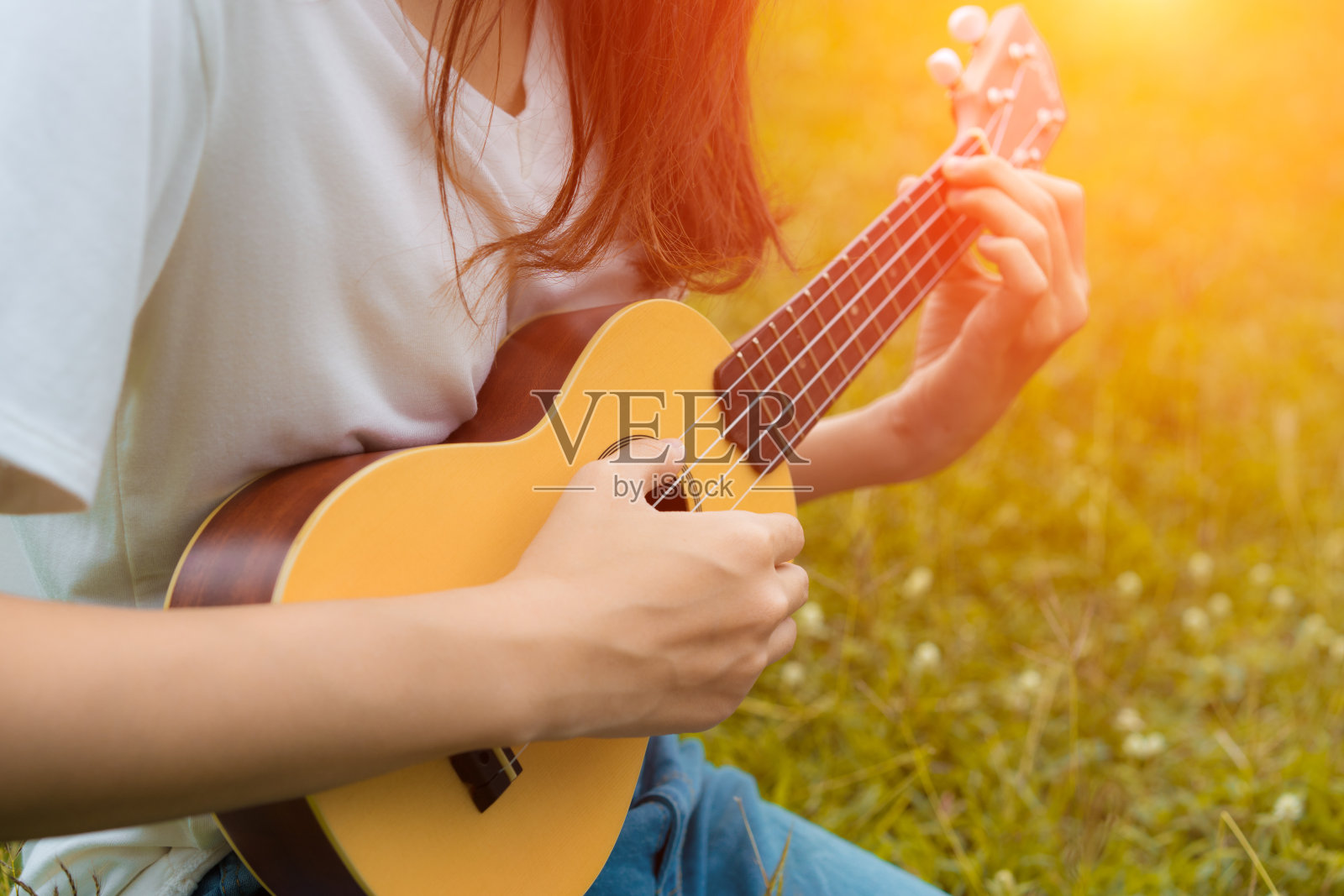 女孩在花园里弹奏尤克里里与原声吉他的特写，年轻女子演奏音乐的生活方式经典照片摄影图片