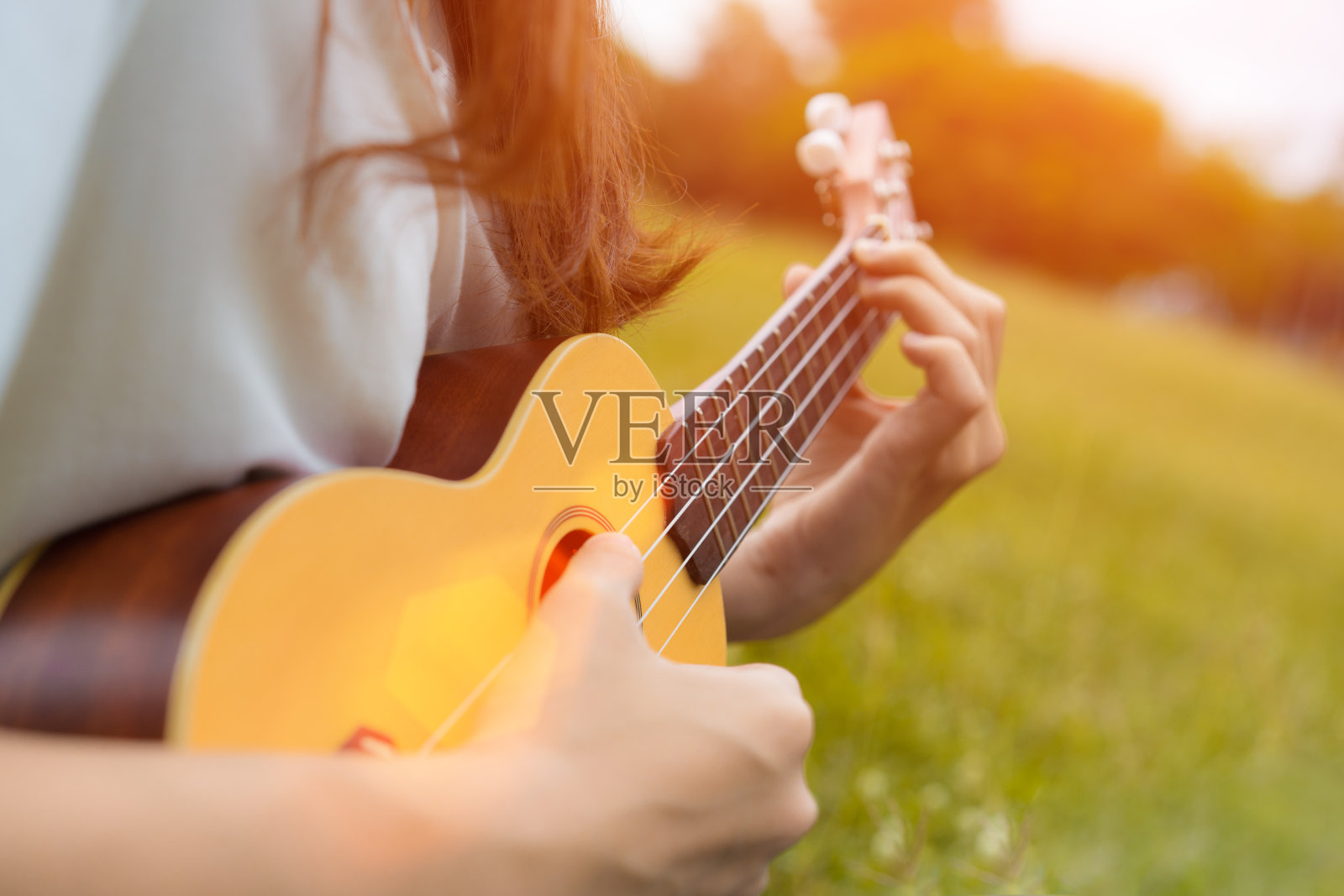 女孩在花园里弹奏尤克里里与原声吉他的特写，年轻女子演奏音乐的生活方式经典照片摄影图片